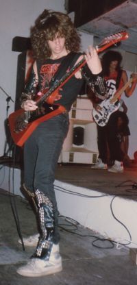 a woman standing on top of a stage with an electric guitar in her hand and two other people behind her