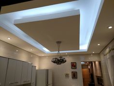 a kitchen with white cabinets and lights on the ceiling