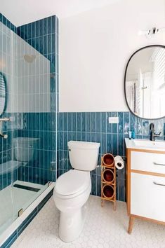 a white toilet sitting next to a walk in shower under a bathroom mirror above a sink