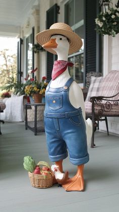 a statue of a duck wearing overalls and a straw hat holding a basket of fruit