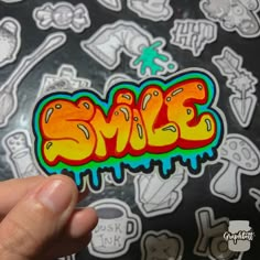 someone holding up a sticker with the word smile painted on it's side