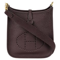 A lovely Hermès mini Evelyne handbag. The exterior of this Evelyne bag is crafted from chocolate Clemence leather complemented with gold-tone hardware and tonal stitching. It features a perforated "H" design, a removable shoulder strap, an open interior, and a snap lock closure. Date stamp is a U without a surrounding shape - 2022 production The bag measures 16cm L x 20cm H x 5cm D. The bag is store fresh and comes complete with a Hermès box, dust bag, removable strap, care book, and original sa Hermes 2002 Bag, Mini Evelyne Hermes, Hermes Evelyn Bag, Date Stamp, H Design, Snap Lock, Hermes Box, Jane Birkin, Fashion Handbags