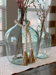 two glass bottles with beads and flowers in them