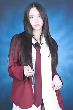 a woman wearing a suit and tie posing for a photo in front of a blue background