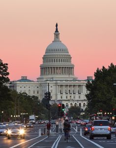 the capitol building in washington d c is seen from across the street at dusk with traffic