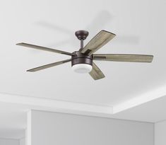 a ceiling fan with three wooden blades in a room