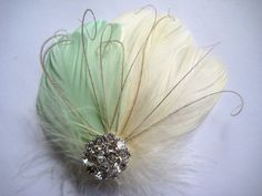 a white and green feather brooch with crystal beads on it's center piece