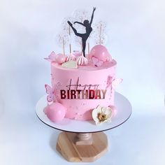 a pink birthday cake with a figure on top