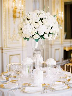 a tall vase filled with pink and white flowers on top of a dining room table