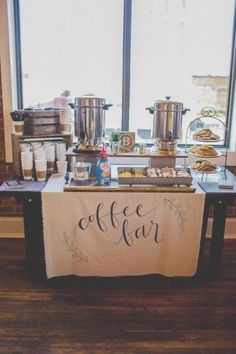 a buffet table with coffee and pastries on it in front of a large window