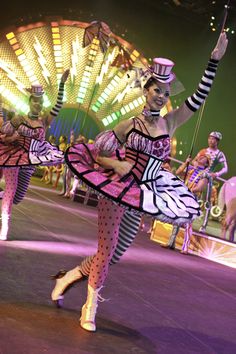 two women dressed in pink and black dancing on stage with ferris wheel in the background