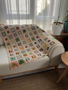 a couch with a crocheted blanket on top of it next to a window