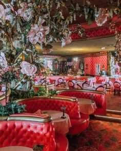 the interior of a fancy restaurant with red velvet booths and floral decorations on the ceiling