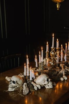 a table topped with skulls and candles on top of a wooden table next to a chandelier