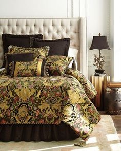 a bed with a gold and black comforter on top of it in a room