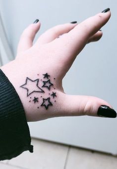 a woman's hand with black ink stars on the left side of her arm