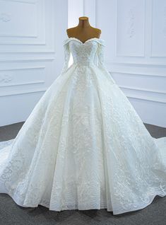 a white wedding dress on display in front of a mannequin headdress