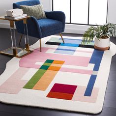 a living room area with a rug, chair and potted plant on the floor