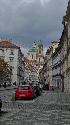 cars parked on the side of a cobblestone street in an old european city