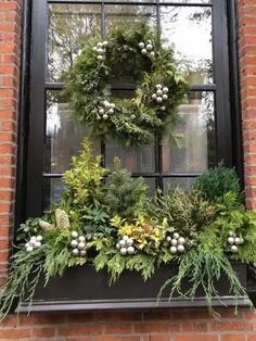 a wreath on the window sill is decorated with greenery and other holiday decorations