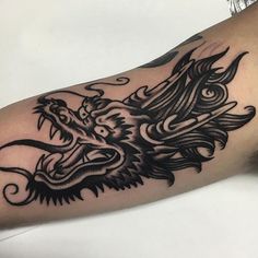 a black and white dragon tattoo on the arm