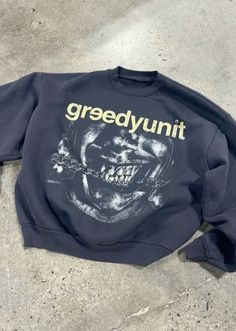 a black sweatshirt with the words greedyunit on it sitting on concrete