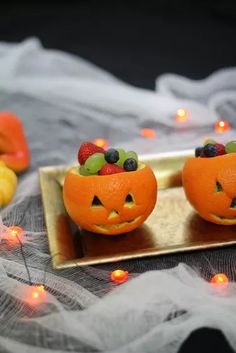 two oranges with faces carved into them sitting on a table next to some candles