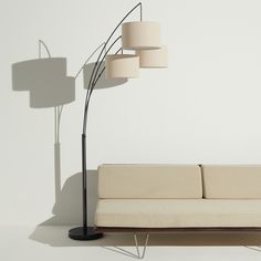 a white couch sitting next to a lamp on top of a wooden table in front of a white wall