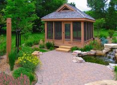 a gazebo in the middle of a garden with a pond and steps leading to it