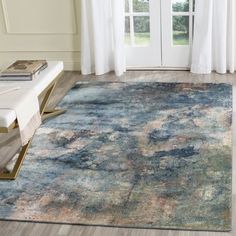 a large rug with an abstract design in blue, pink and green colors on a wooden floor