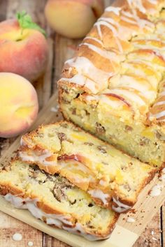 sliced loaf of peach bread sitting on top of a cutting board next to two peaches