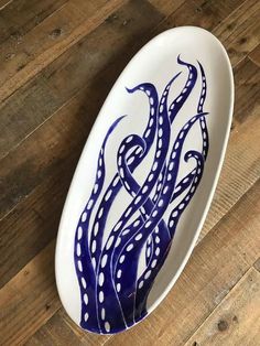 a blue and white bowl with an octopus design on the bottom sitting on a wooden floor