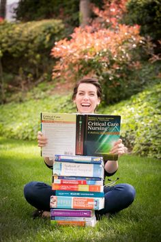 a woman is sitting in the grass holding several books