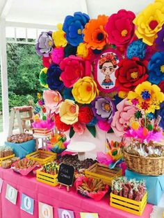 a table topped with lots of colorful flowers next to a white tent covered in food