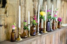 there are many bottles with flowers in them on the shelf and one is filled with candles