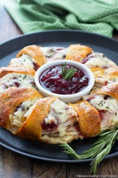 a cranberry and cheese appetizer on a black plate with rosemary garnish