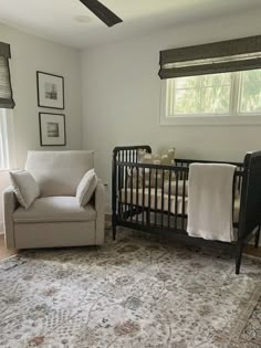 a baby's room with a chair, crib and rug