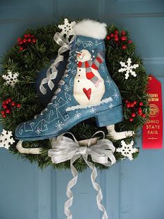 a christmas wreath with a snowman boot hanging from it's side on a blue door