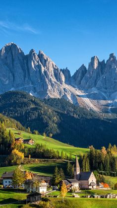 the mountains are covered in snow and green grass, while houses stand on either side