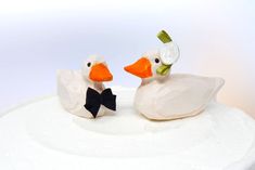 two white ducks sitting on top of a cake