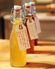 three bottles of honey sitting on top of a wooden table with tags attached to them