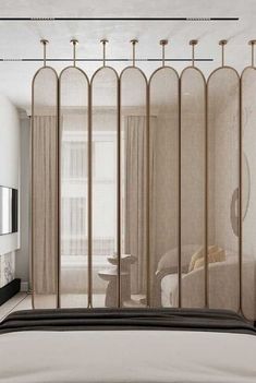 a bed sitting next to a window covered in sheer curtains and gold poles on top of it