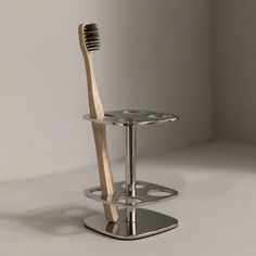 a toothbrush holder with a wooden toothbrush on it and a metal stand underneath