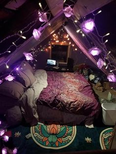 a bed in a room with purple lights on the ceiling and a laptop sitting on top of it