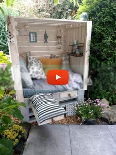 an outdoor bed made out of pallets in the garden with plants and flowers around it