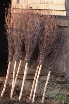 four brooms are lined up in front of a wooden building with the door open