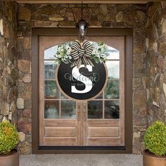 a front door with two potted plants and a welcome sign