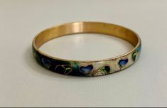 "Fabulous bangle by Taiwanese artist Robert Kuo, brings an organic, modern look to an ancient art. Cool colors of blue, green, purple and cream enamel surround stylized leaves and hearts outlined in gold. Just gorgeous and quite unusual.  Bracelet measures 2 5/8\" inside diameter and 8\" circumference. Listing is offered as-is. Please ask any questions prior to purchasing." Hand Painted Gold Bracelet, Elegant Hand Painted Bracelet, Hand Painted Gold Jewelry Wearable Art, Wearable Art Green Bangle Jewelry, Gold Hand Painted Bracelets As Gift, Gold Hand Painted Bracelets For Gift, Hand Painted Gold Bracelets For Gift, Artistic Hand Painted Jewelry Bracelet, Heart Outline