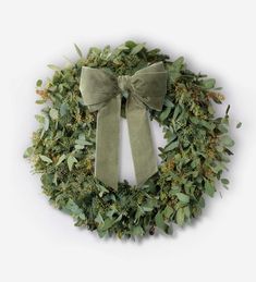 a wreath with a green bow on it and some greenery around the edges is shown