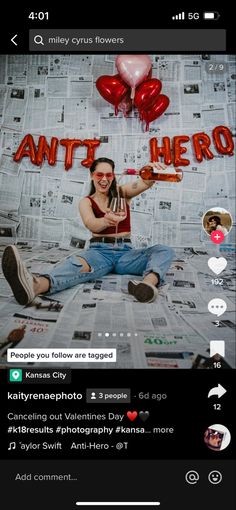 a woman sitting on top of a bed next to red balloons and the words anti hero